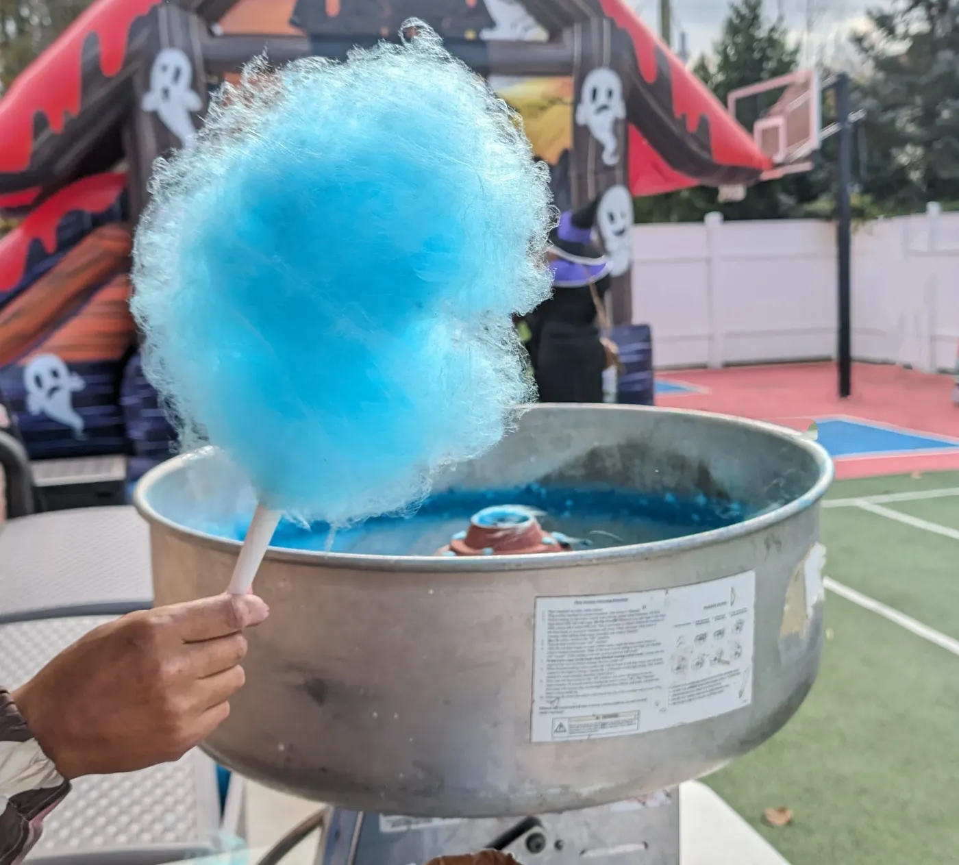 Blue cotton candy held above a spinning machine
